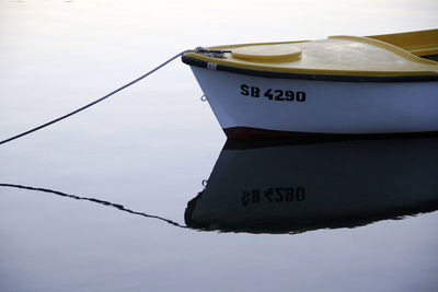 Reflection of boat moored on calm lake