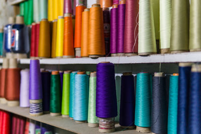 Close-up of multi colored spools on shelves at shop