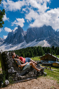 People relaxing on mountain against sky