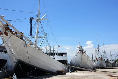 Sailboats moored in harbor against sky