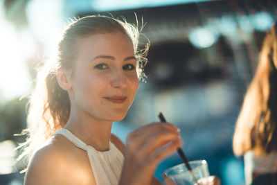Portrait of smiling beautiful woman having drink on sunny day