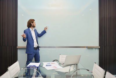 Businessman writing on whiteboard in conference room