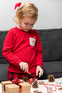 Little child wearing christmas holiday pajamas, doing crafts christmas tree decorations.