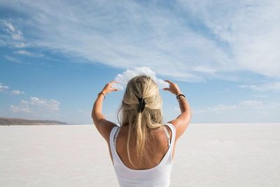 Optical illusion of woman holding clouds on sunny day
