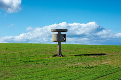 Information sign on field against sky