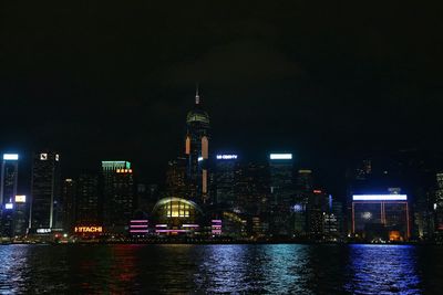 Illuminated cityscape by victoria harbour against sky at night