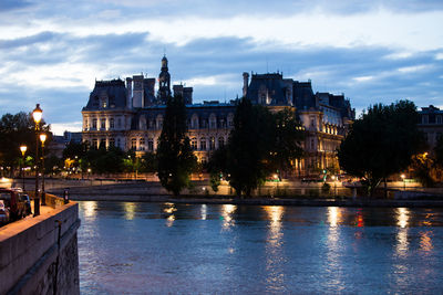 River by illuminated city against sky