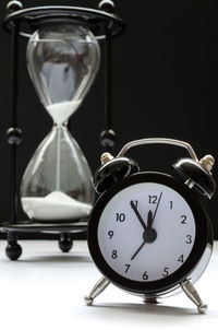 Close-up of clock and hourglass on table