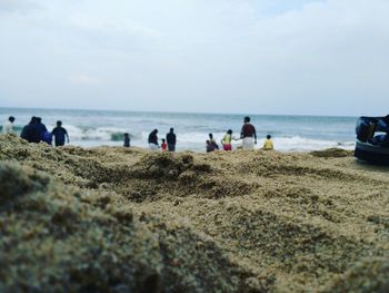 People at sandy beach against sky