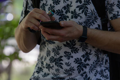 Midsection of man using mobile phone outdoors