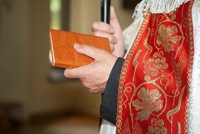 Midsection of priest holding bible in church