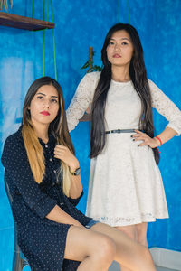 Portrait of beautiful young women against blue wall