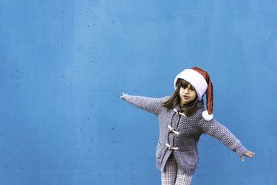 Portrait of woman standing against blue wall