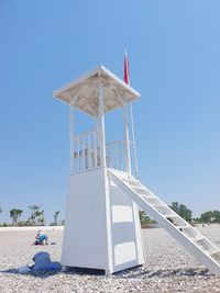 Low angle view of white lifeguard tower against clear blue sky