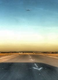 Airplane flying over road against sky