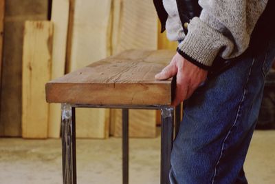 Midsection of man holding wooden table