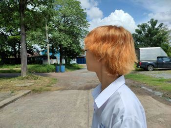 Rear view of man standing on road against trees