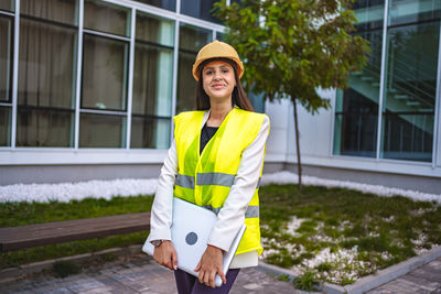 Portrait of young woman standing against building