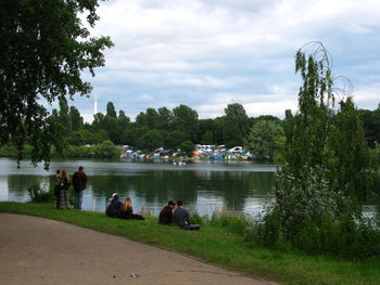 People on riverbank against sky