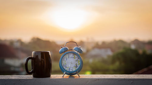 Close-up of clock on retaining wall against orange sky