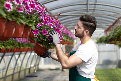 Man holding flower while standing against wall