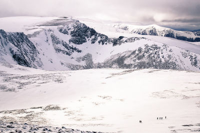 Aerial view of snowcapped mountains against cloudy sky