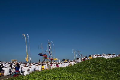 Group of people in amusement park against clear blue sky