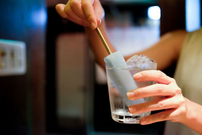 Cropped image of woman dipping popsicle in drink