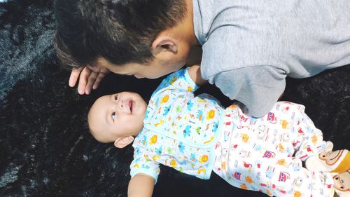 High angle view of cute baby lying on man