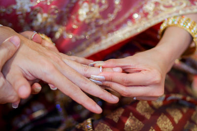 Midsection of wedding couple exchanging finger rings during ceremony