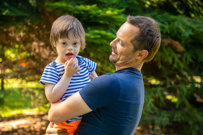 Side view of father holding son standing outdoors