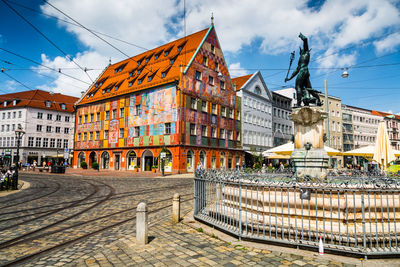 Statue in city against cloudy sky