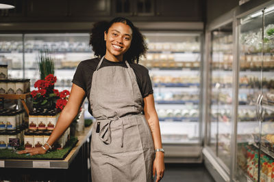 Portrait of smiling saleswoman standing in grocery store