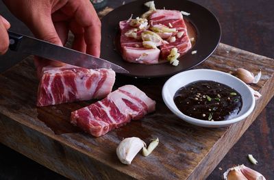 Cropped hand of butcher chopping beef on cutting board