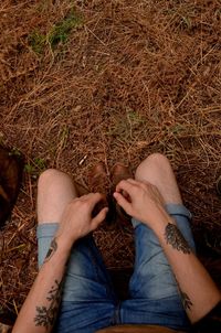 Low section of tattooed man sitting in forest