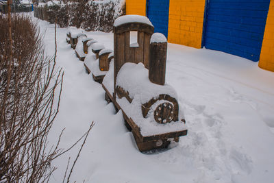 Snow covered field by fence