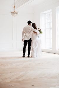 Rear view full length of bride and bridegroom standing in room