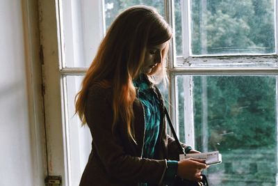 Side view of woman holding document at home