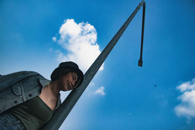 Low angle view of man wearing hat against blue sky