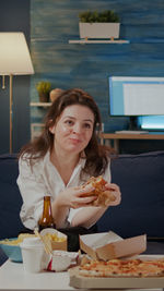 Smiling woman eating pizza at home