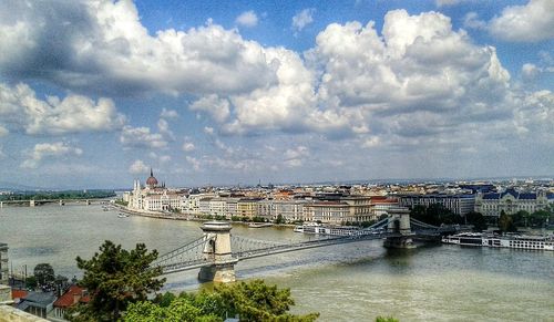 Bridge over river in city against sky