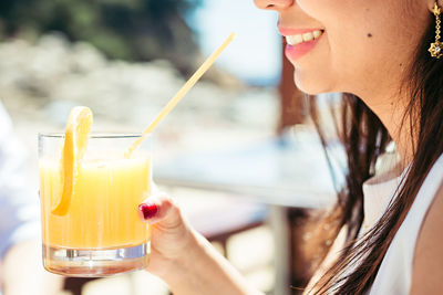 Midsection of smiling young woman holding cocktail