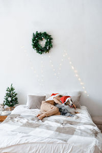 A boy and a dog in red santa hat sleeping on bed. best friends. christmas mood. festive atmosphere