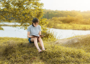 Teenage girl reading book on field