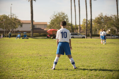 Young player in soccer uniform streching in the park