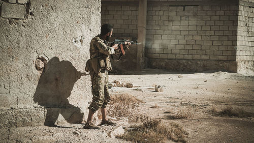 Terrorist holding rifle while standing by building