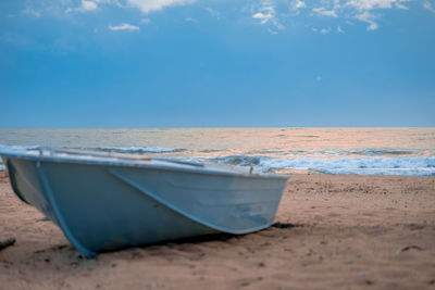 Close-up of boat moored on beach against sky
