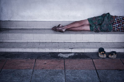 Low section of man sleeping on footpath