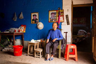 Full length portrait of man sitting on table