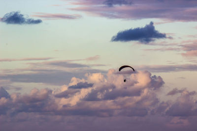 Low angle view of person paragliding against sky during sunset